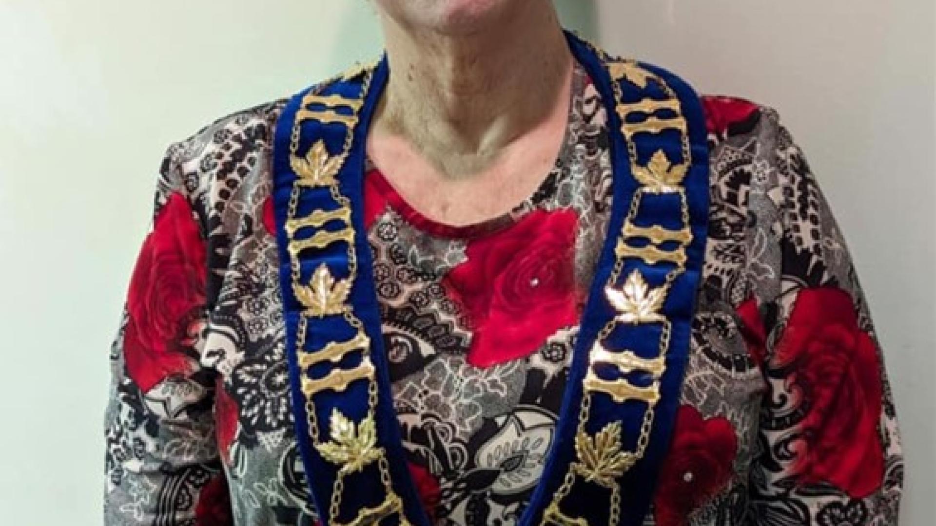 Headshot of Mayor Cheryl Philip. There is a woman with short hair with a floral print shirt smiling and wearing a Kearney sash