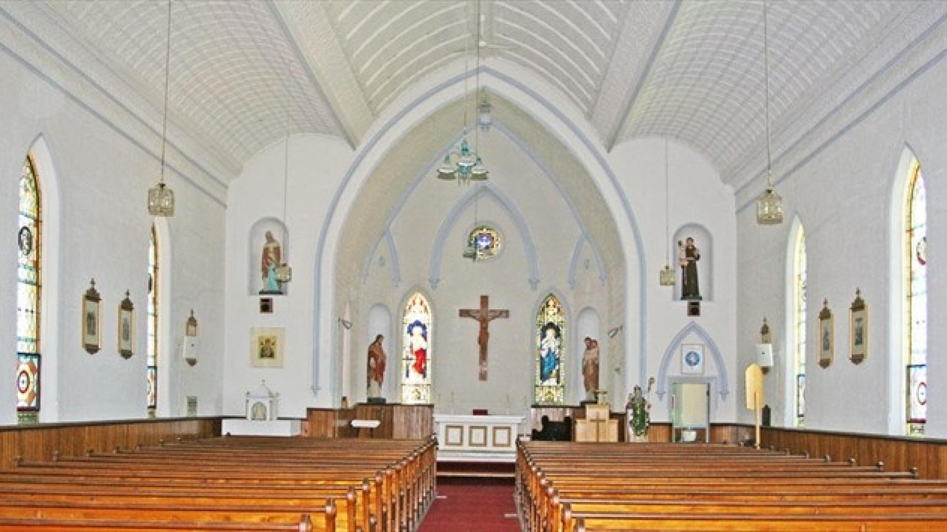 Interior of St Patrick's Roman Church. The ceilings a tall and vaulted. There is a crucifix behind the altar at the back fo the church.