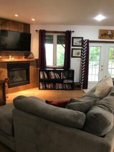 Interior of living room. There is a sofa, fireplace, TV, and a small bookcase spread throughout the room.